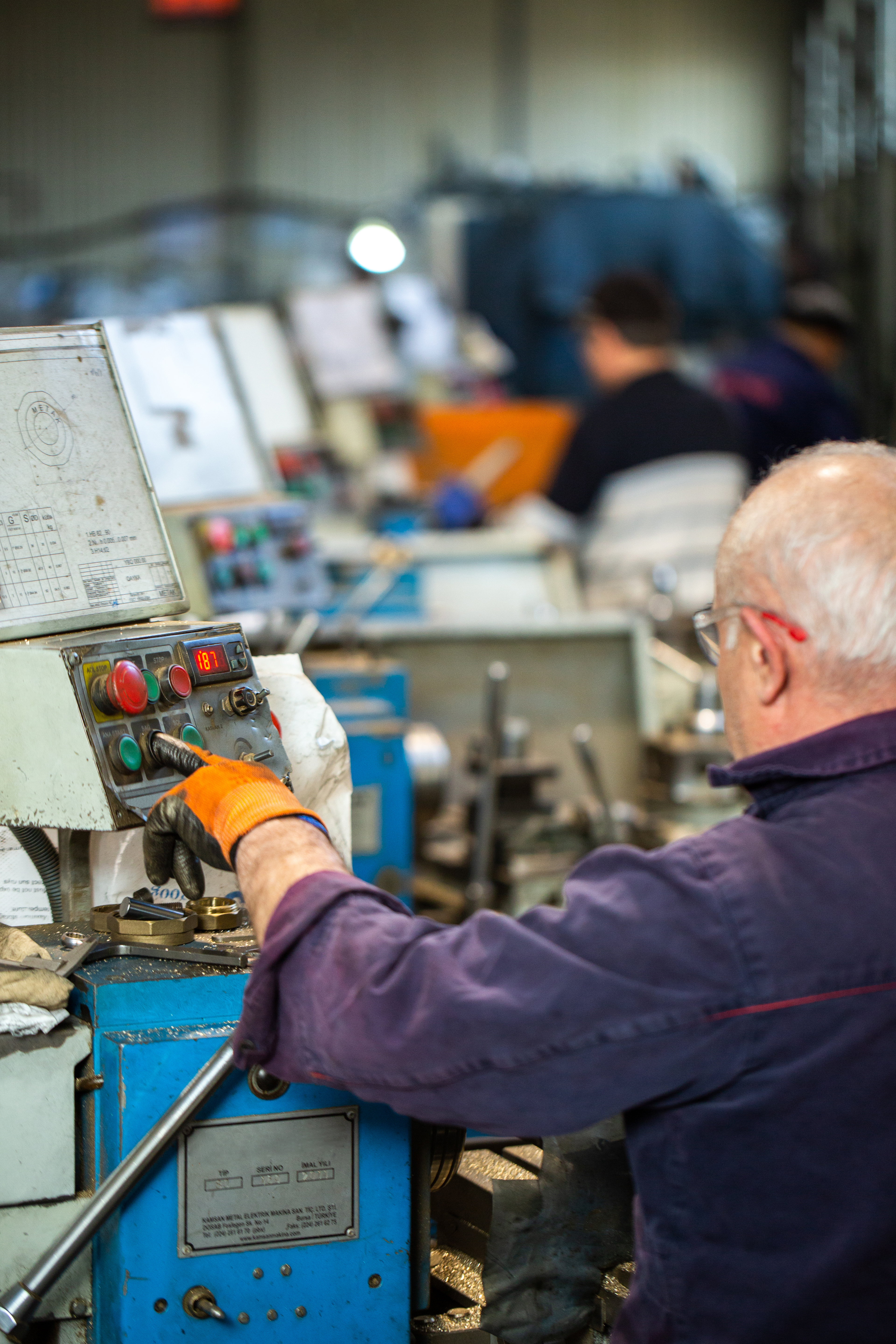 An engineer operating a lathe control panel on the shop floor