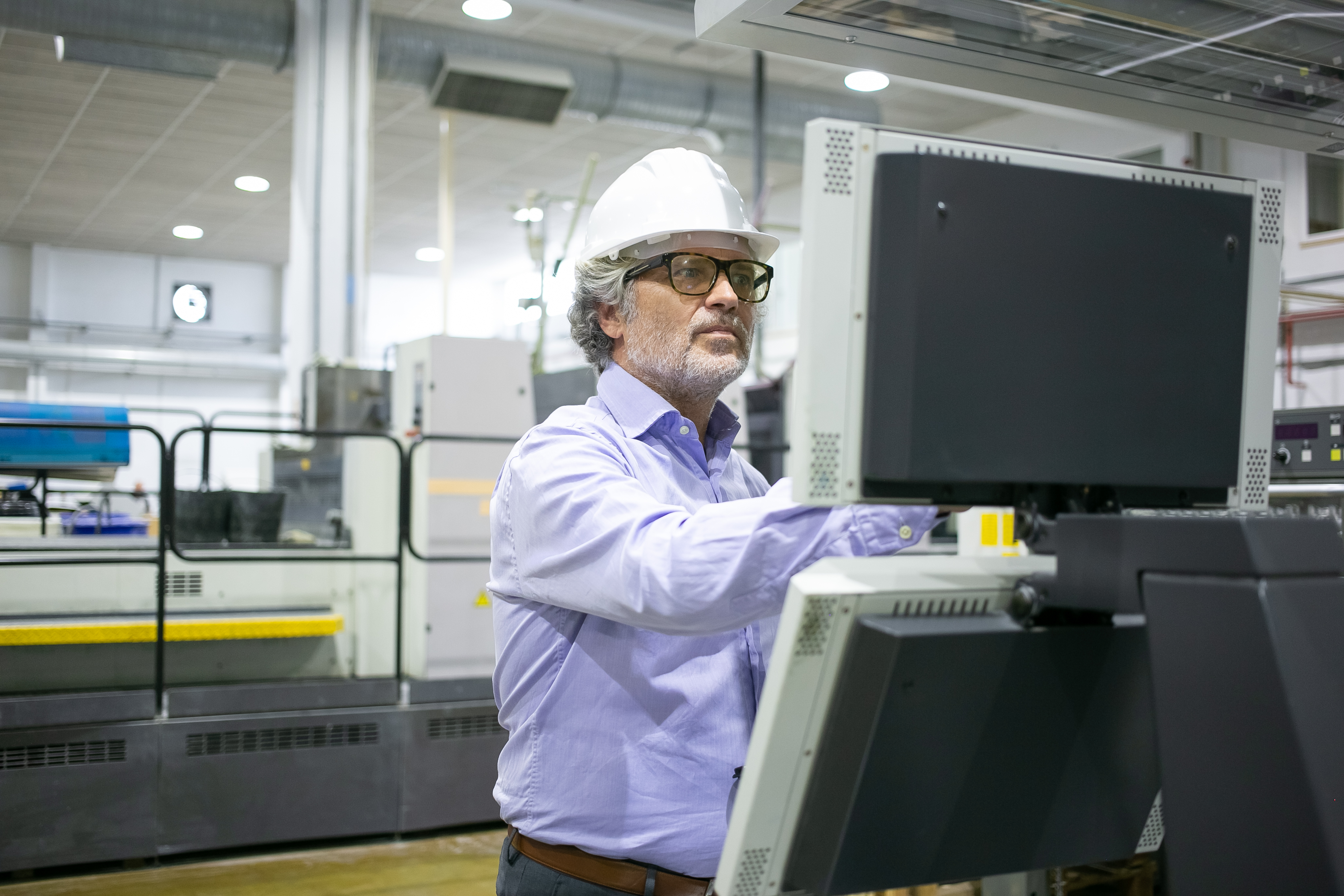 A plant manager in a hard hat reviewing an industrial control screen